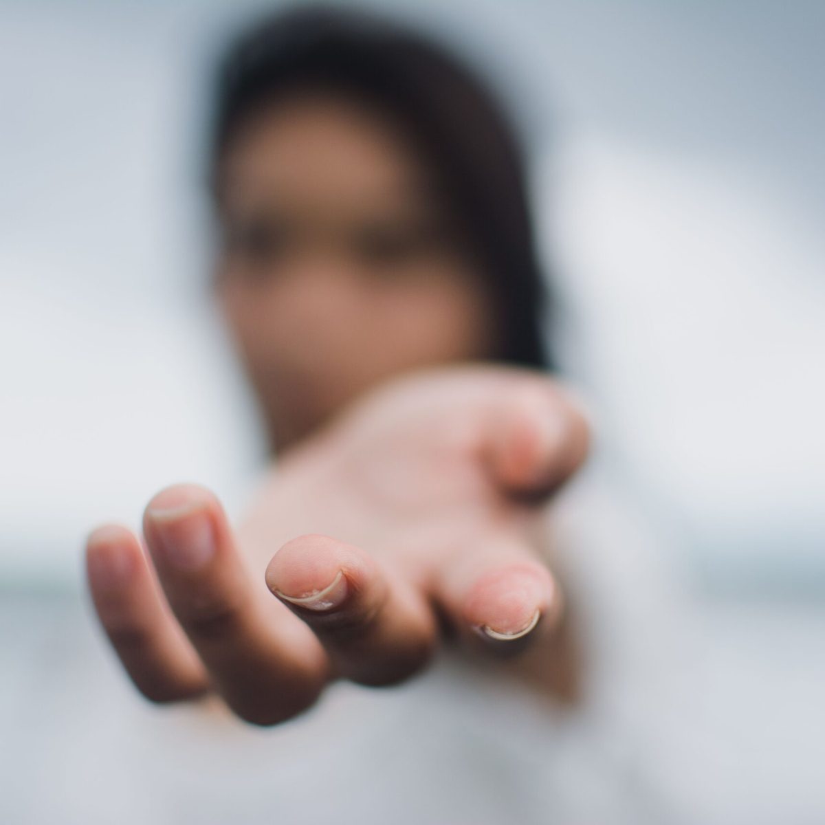 A soft focus image highlighting a reaching hand, symbolizing connection or help.